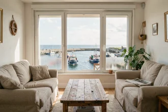 Salon d'un appartement à Concarneau avec vue mer panoramique sur le port, ambiance chaleureuse et authentique